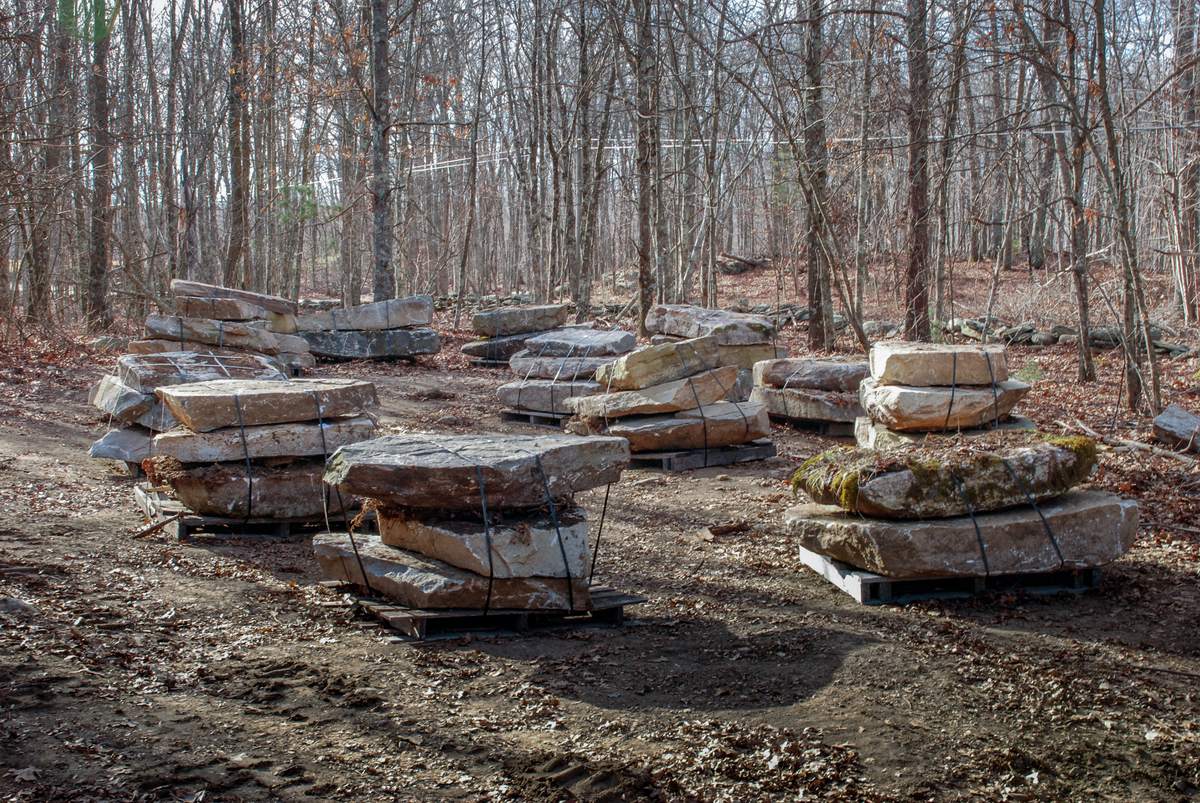 Pallets of ledge stone selected in the field, strapped and stacked in the woods