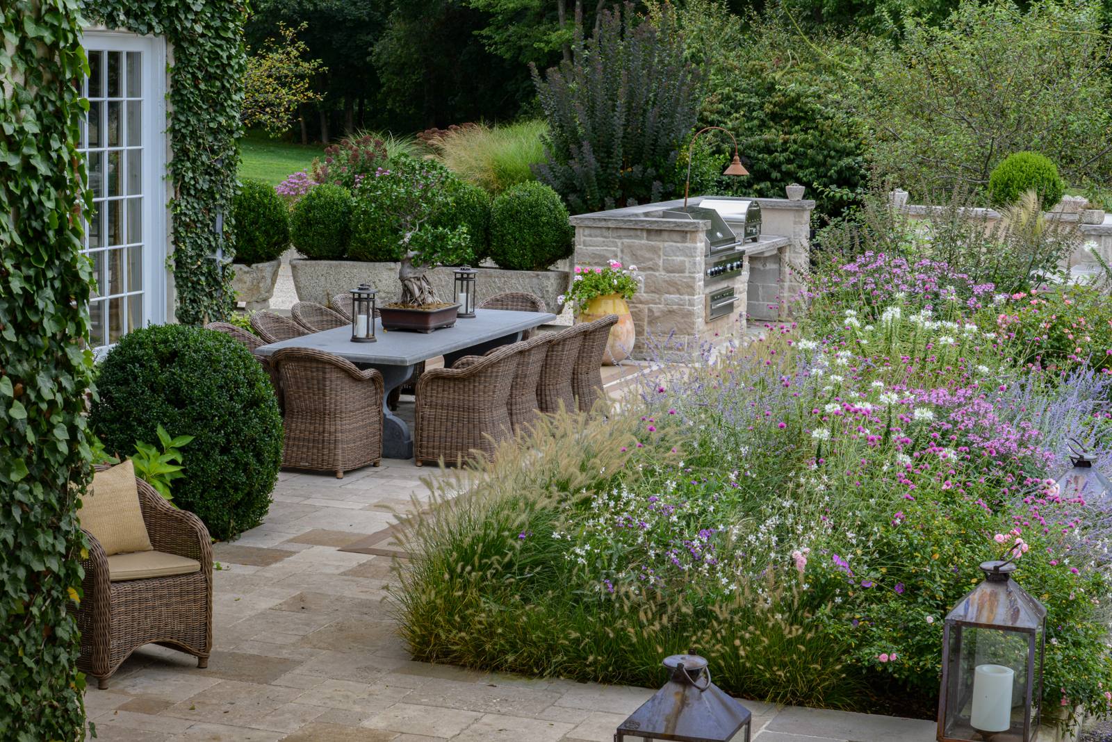 Dining terrace and outdoor kitchen above a flowering border