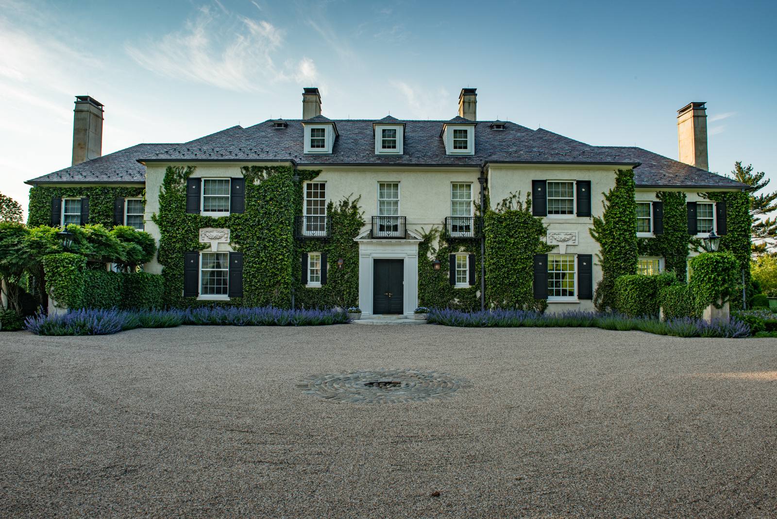 Ivy-covered stucco house with a gravel forecourt and catmint borders