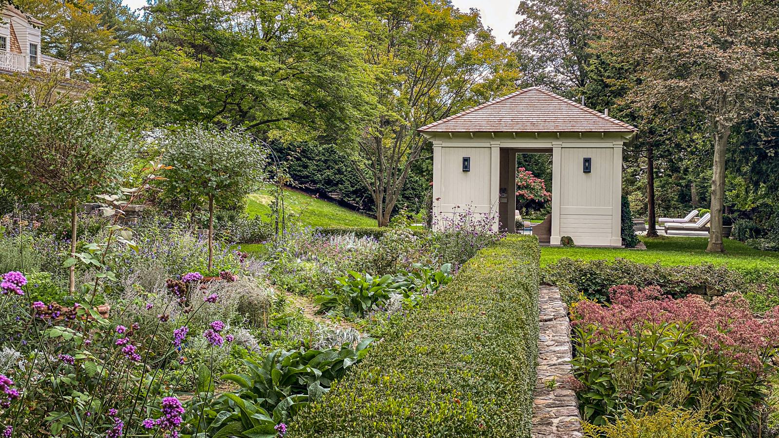 Perennial border and clipped hedge beside a garden pavilion